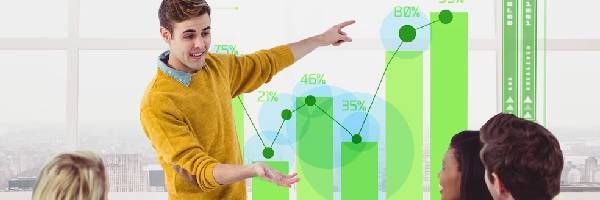 A man is giving a presentation to a group of people while pointing at a graph.