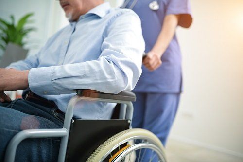 Un'infermiera spinge un anziano in sedia a rotelle