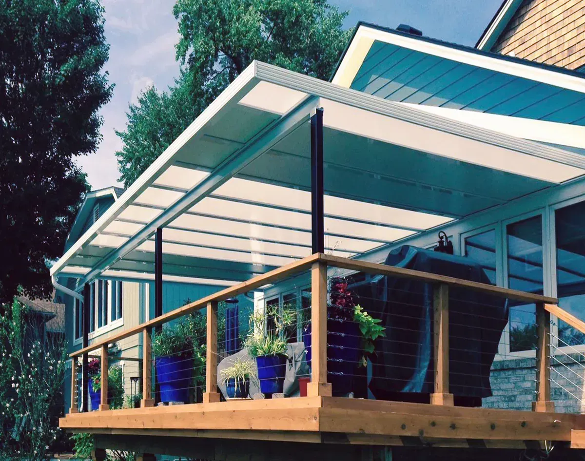 Deck with a white awning, wooden railing, and blue pots.