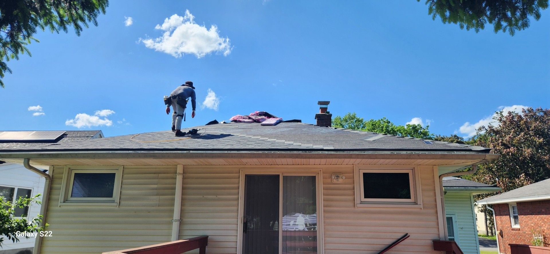 A man is standing on the roof of a house.
