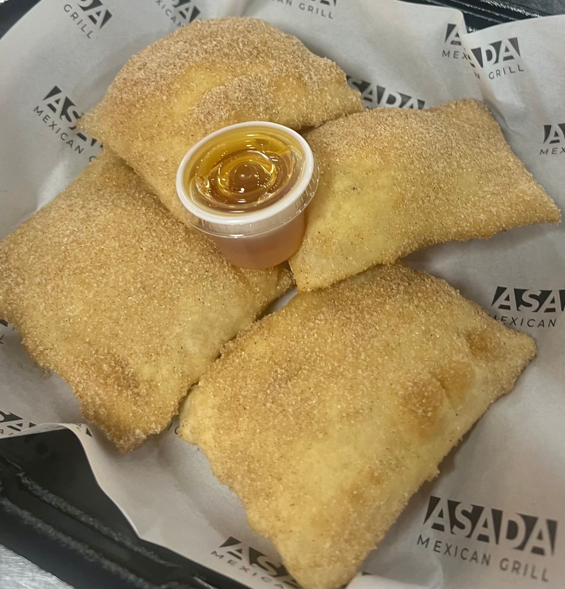 A person is holding a tray of churros with dipping sauce.
