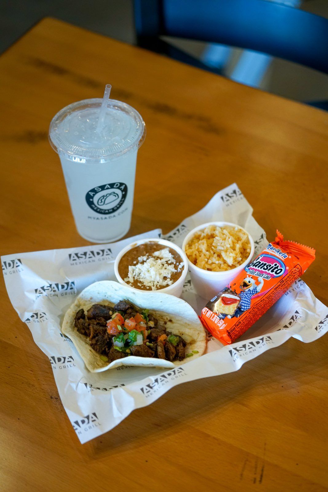 A wooden table topped with a tray of food and a drink.