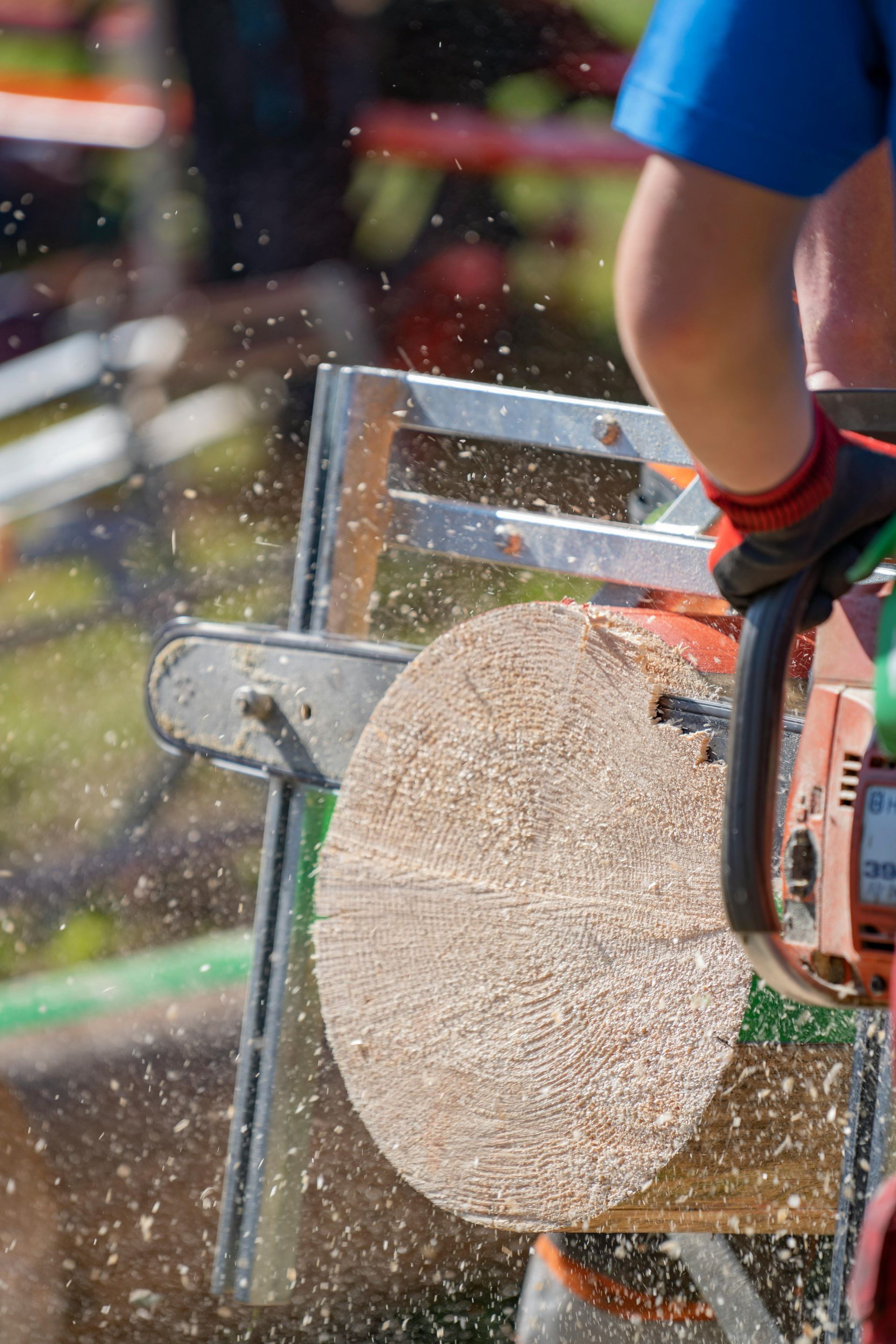 Person using a chainsaw to cut a log, creating sawdust.