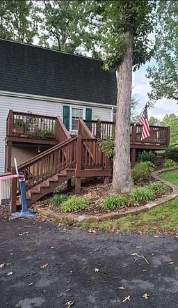 back of home that has a wooden wraparound deck