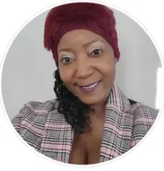 A woman wearing a red hat and a plaid jacket is smiling for the camera.