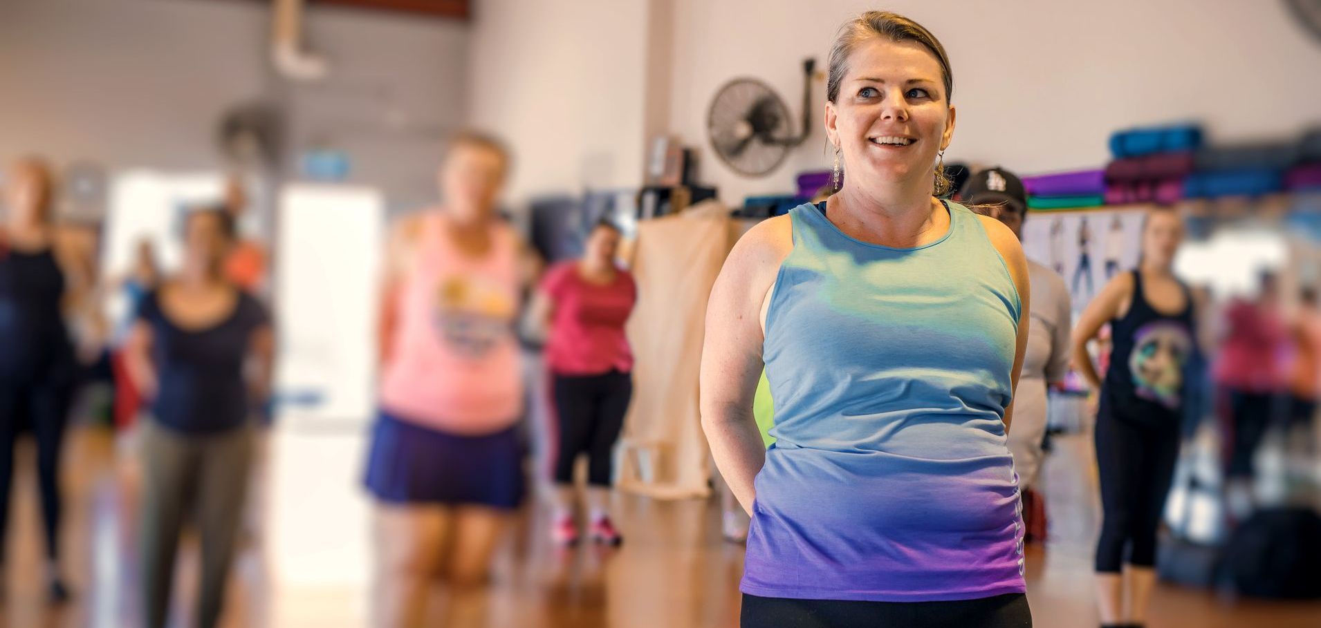 Gym class with smiling woman in focus