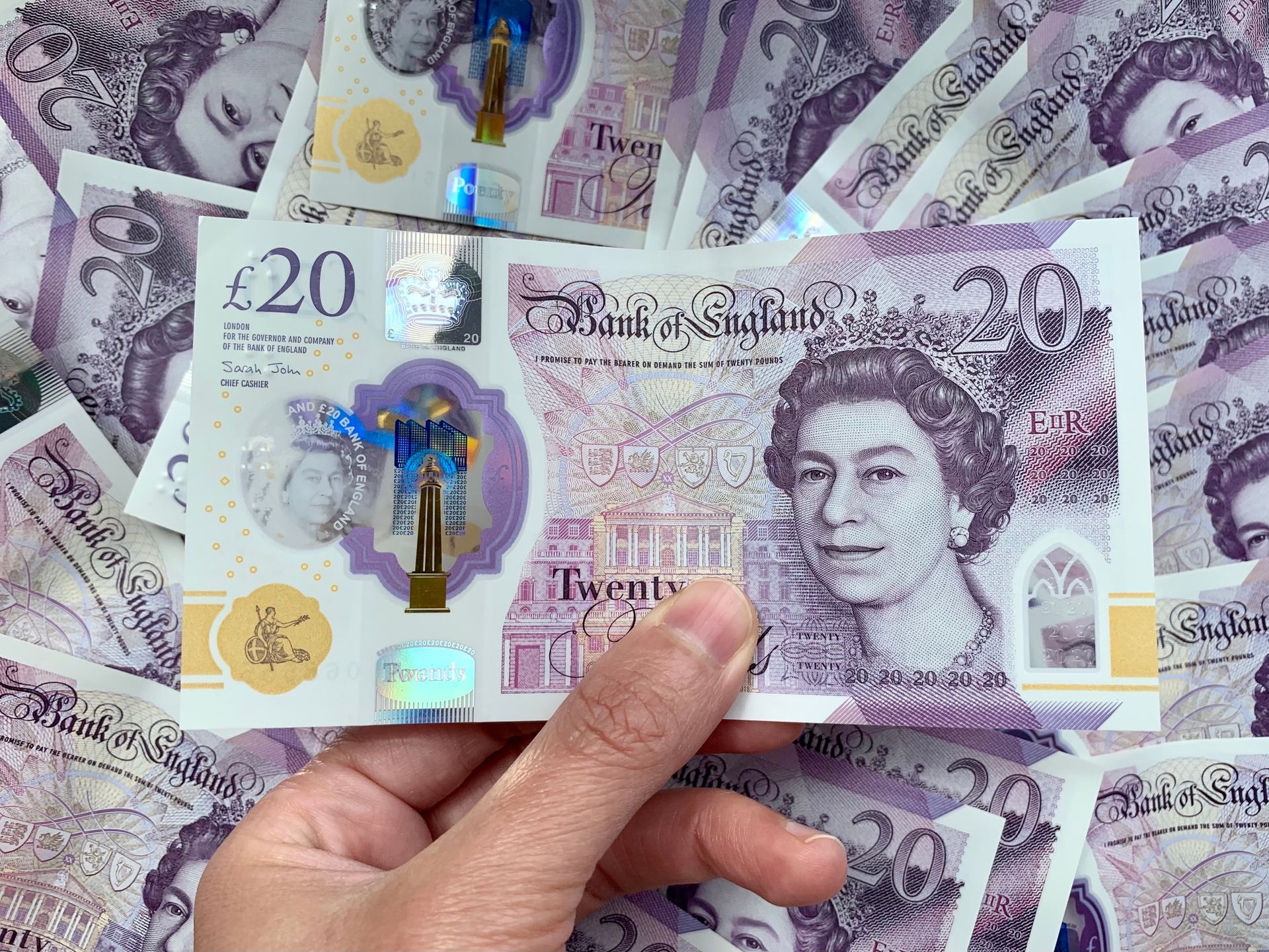Hand holding a £20 note