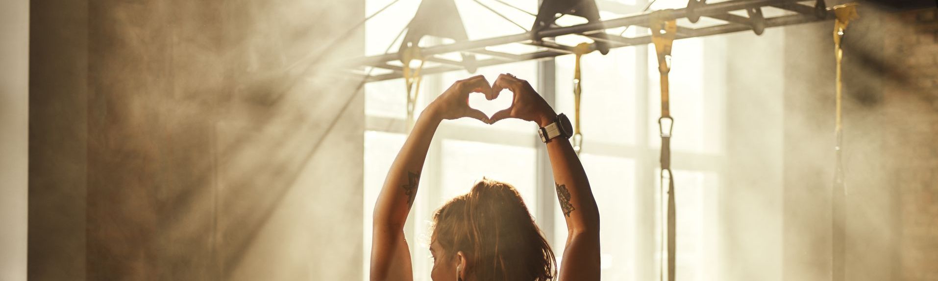 Fit woman making heart shape with hands in the gym