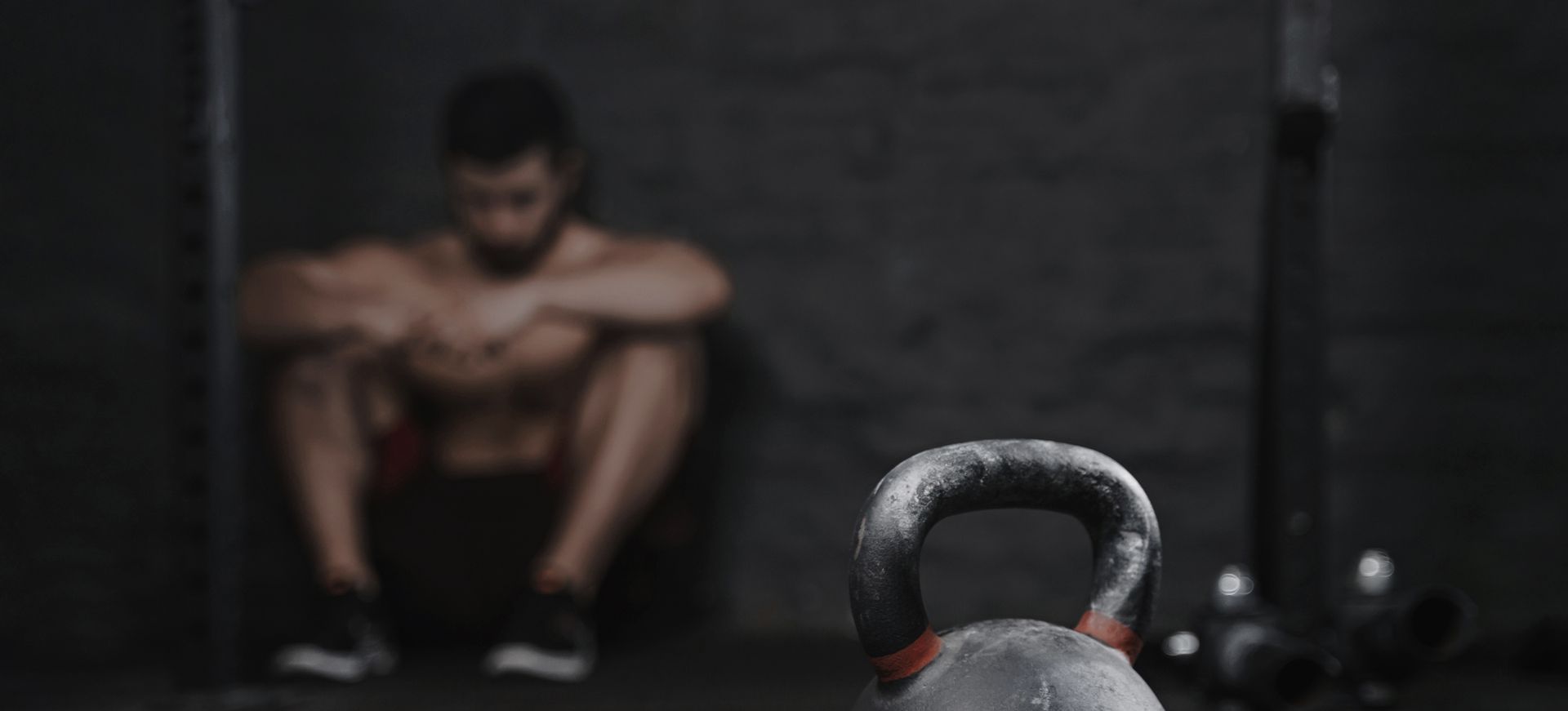 out of focus man having a breakdown sat in a gym