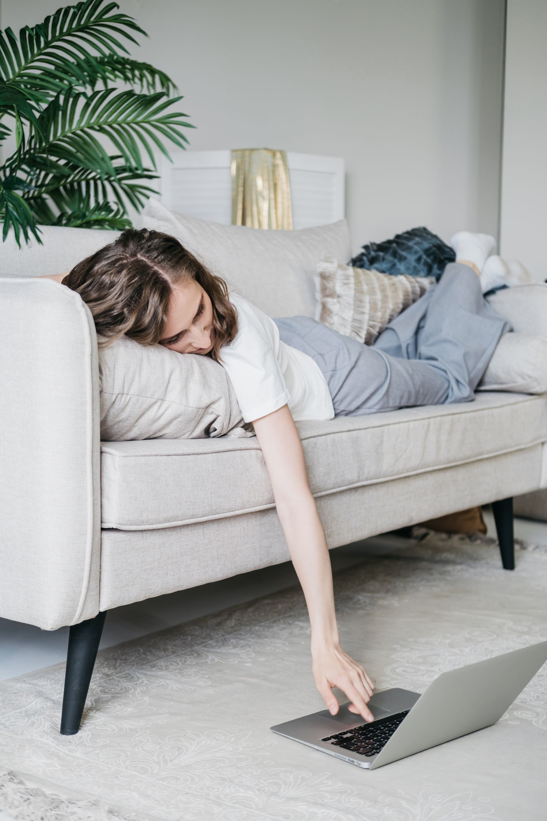 Woman lying on sofa scrolling on laptop