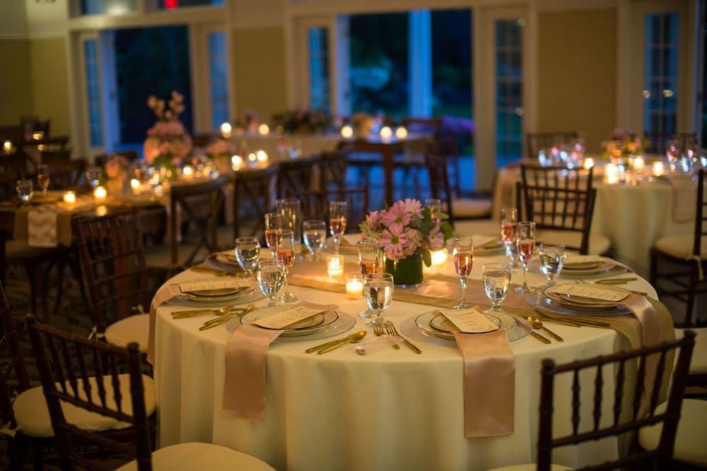 Elegant wedding reception tables set with glassware, candles, and floral centerpieces.