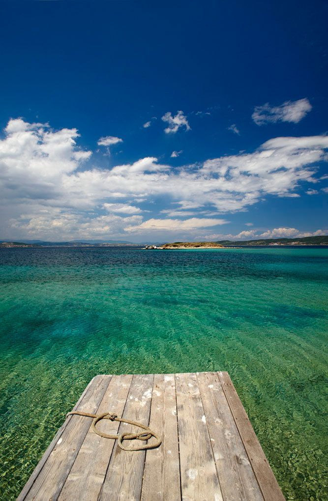A wooden pier leading into a turquoise ocean.