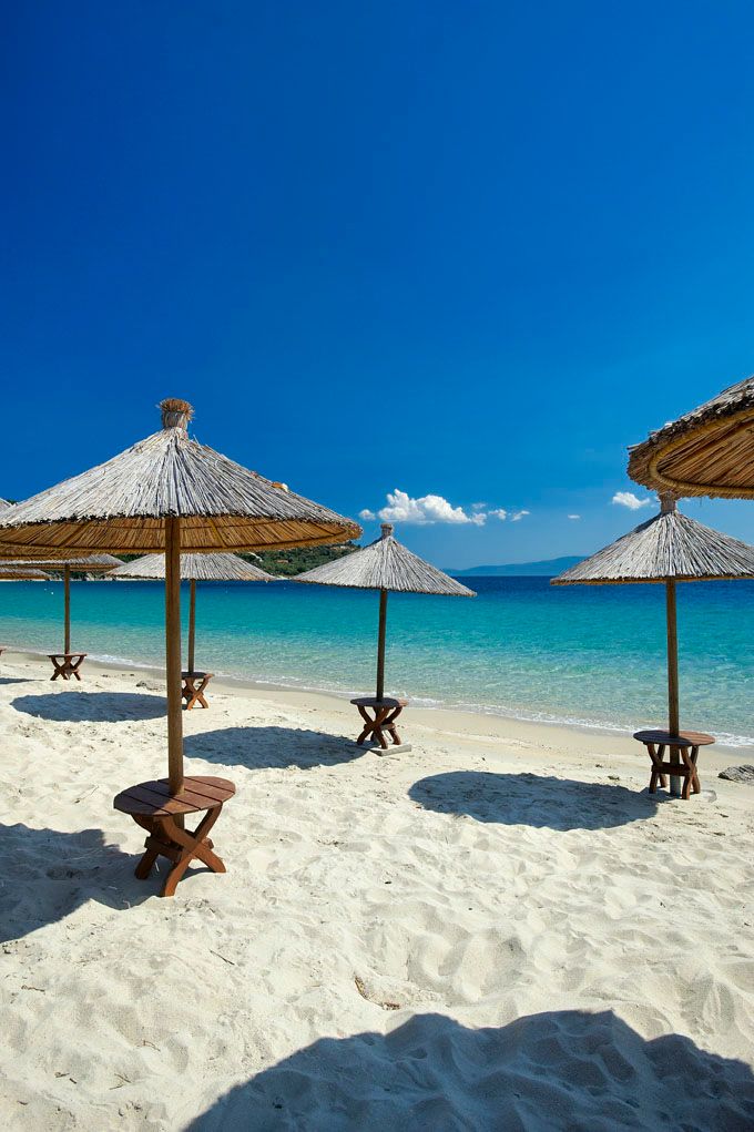 A beach with umbrellas and benches on a sunny day.