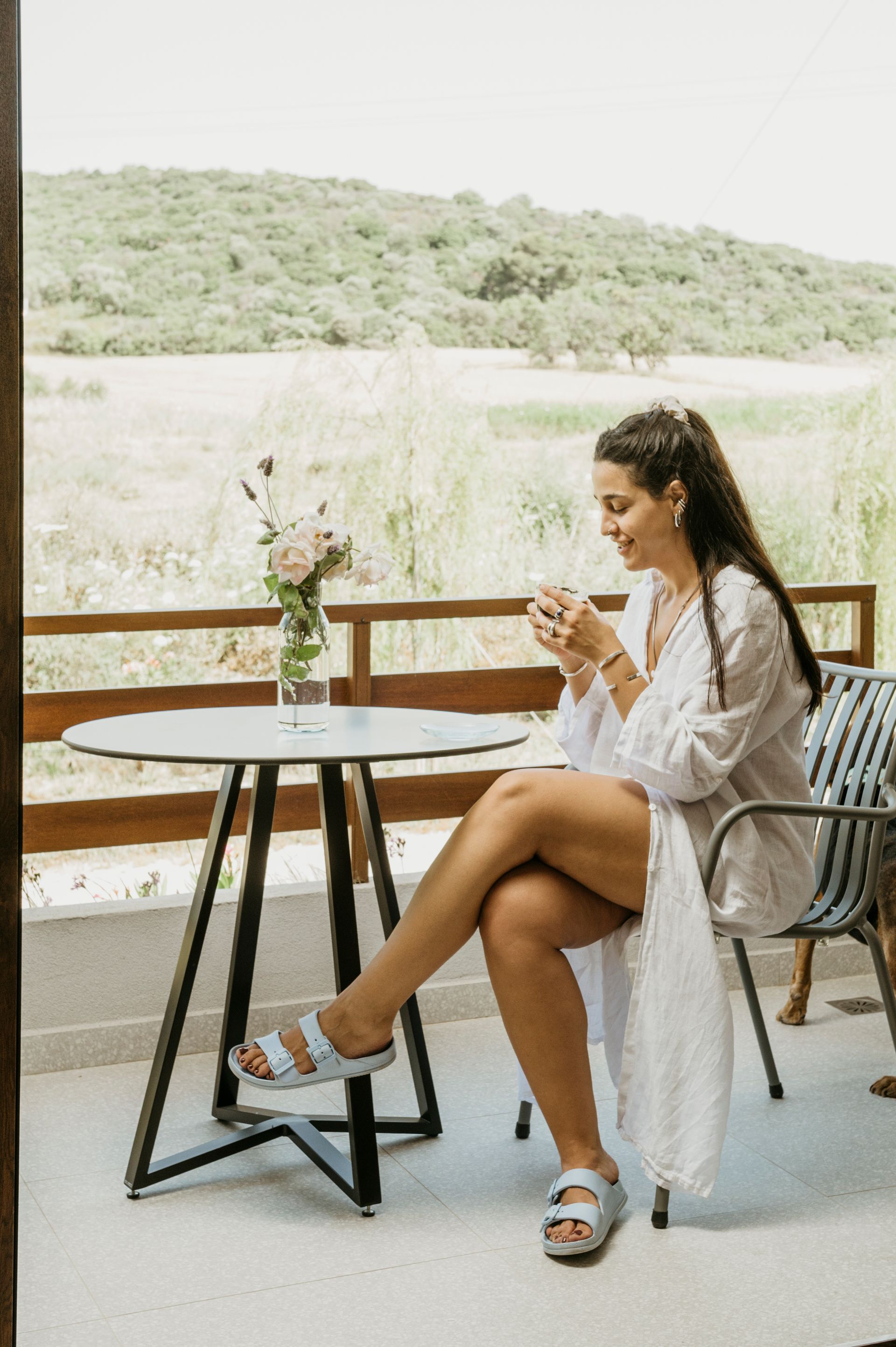A woman is sitting at a table drinking a cup of coffee.