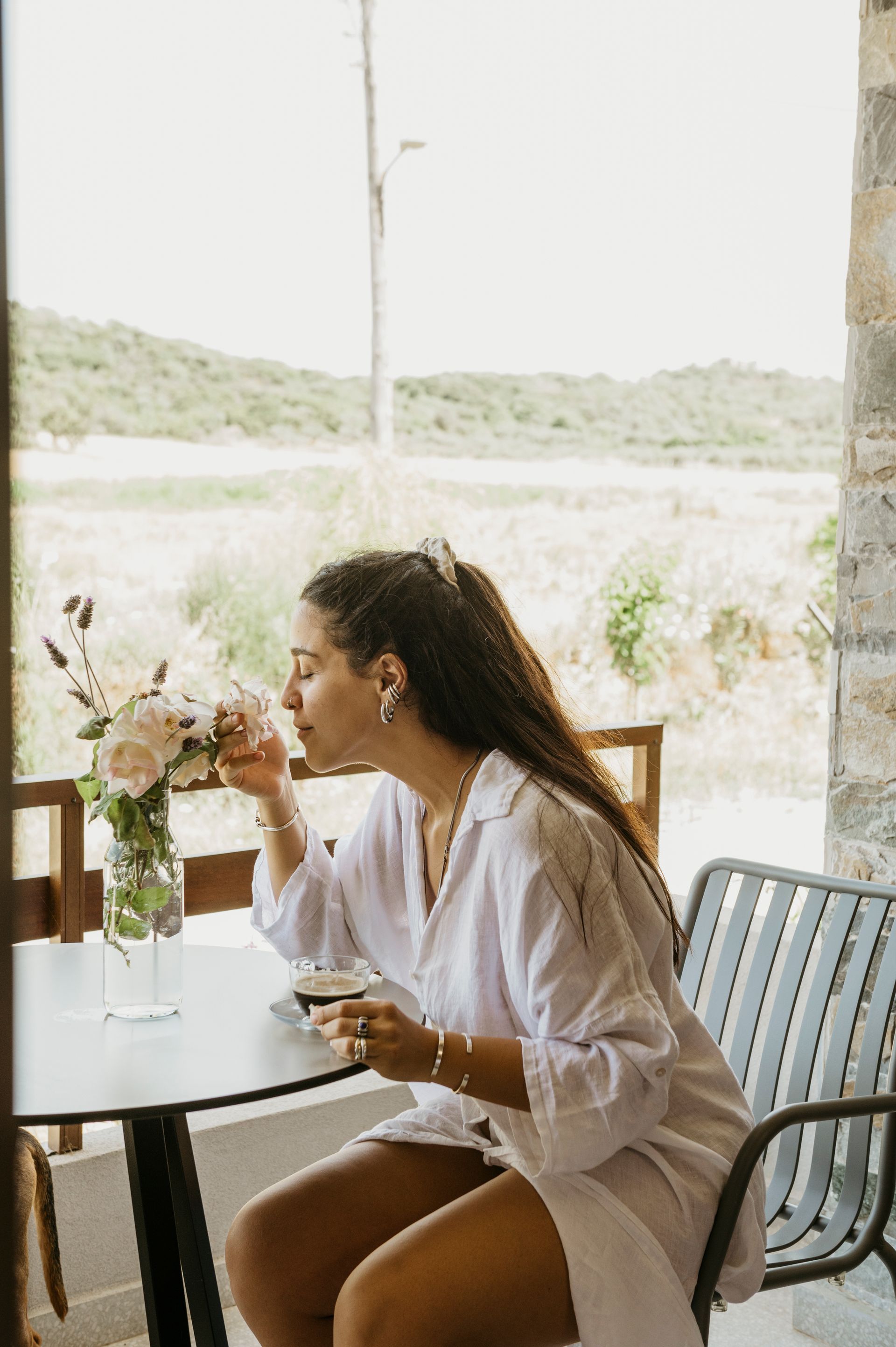 A woman is sitting at a table drinking a cup of coffee.