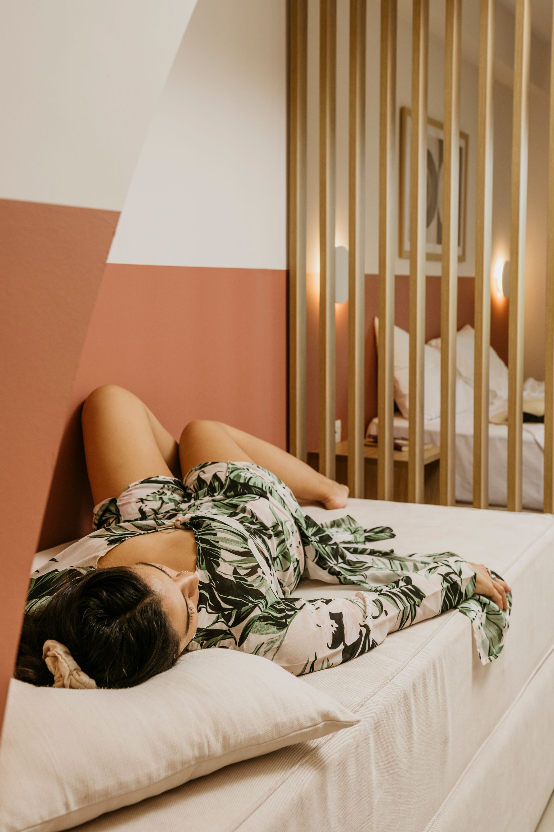 A woman is laying on a bed in a hotel room.