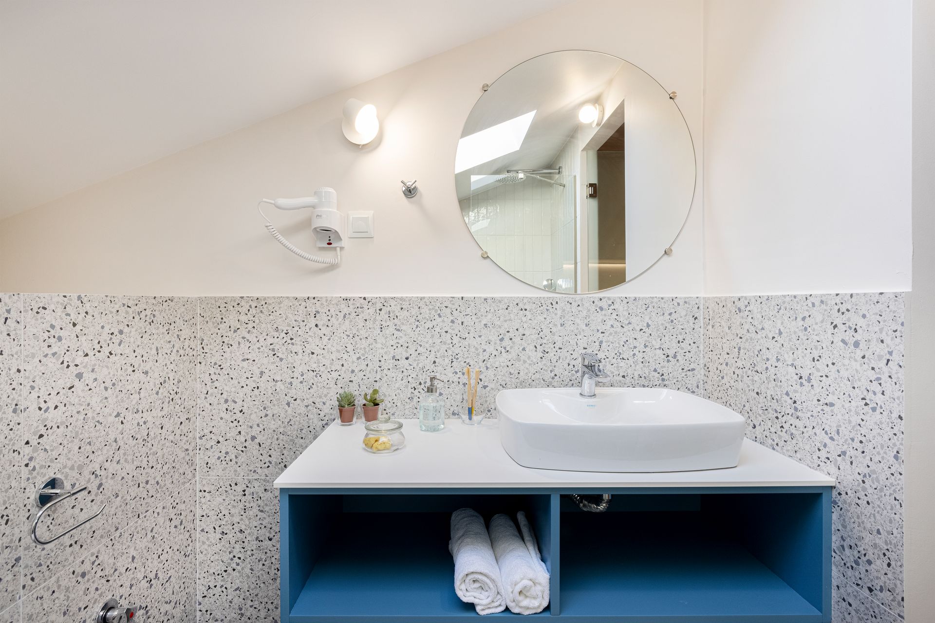 A bathroom with a sink , mirror and towels on the counter.