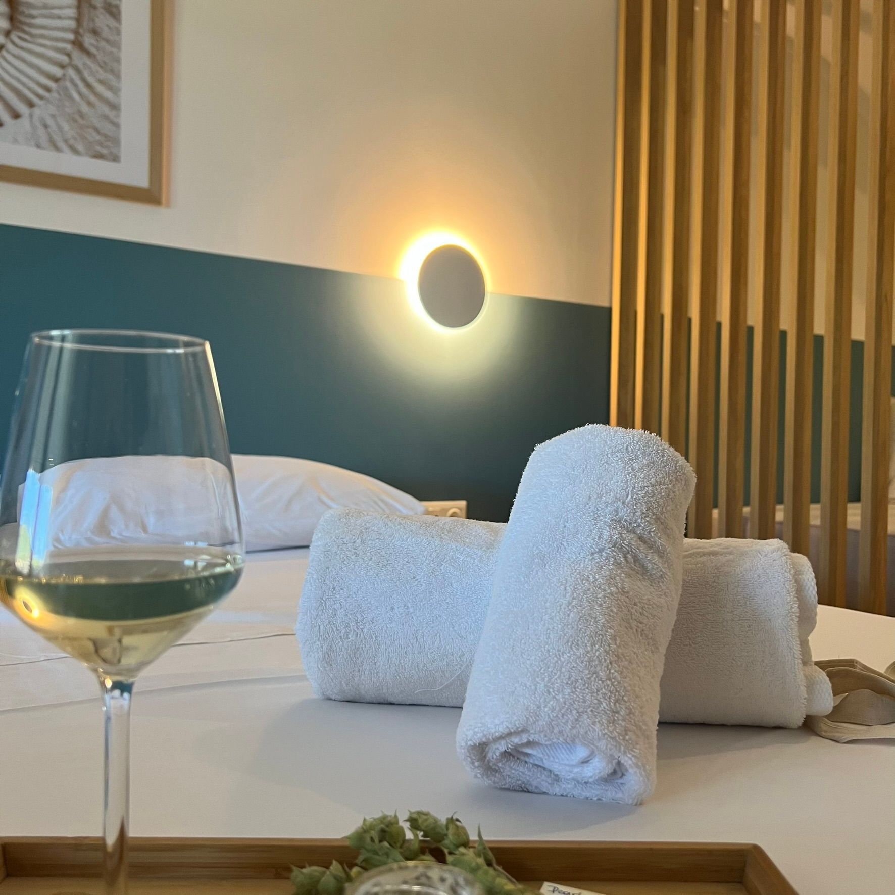A bed with towels and a glass of wine on it