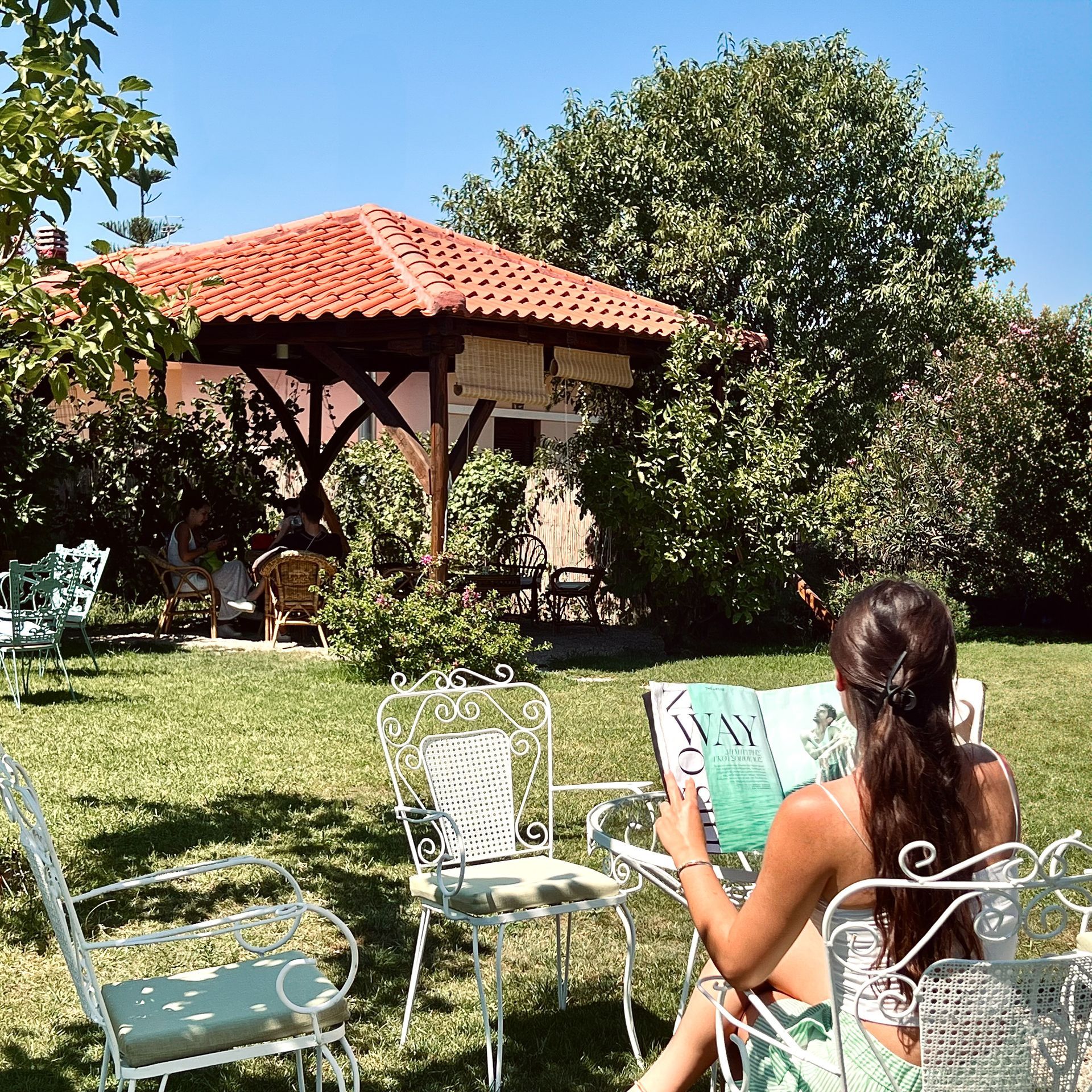 A woman sits in a chair reading a book in a garden
