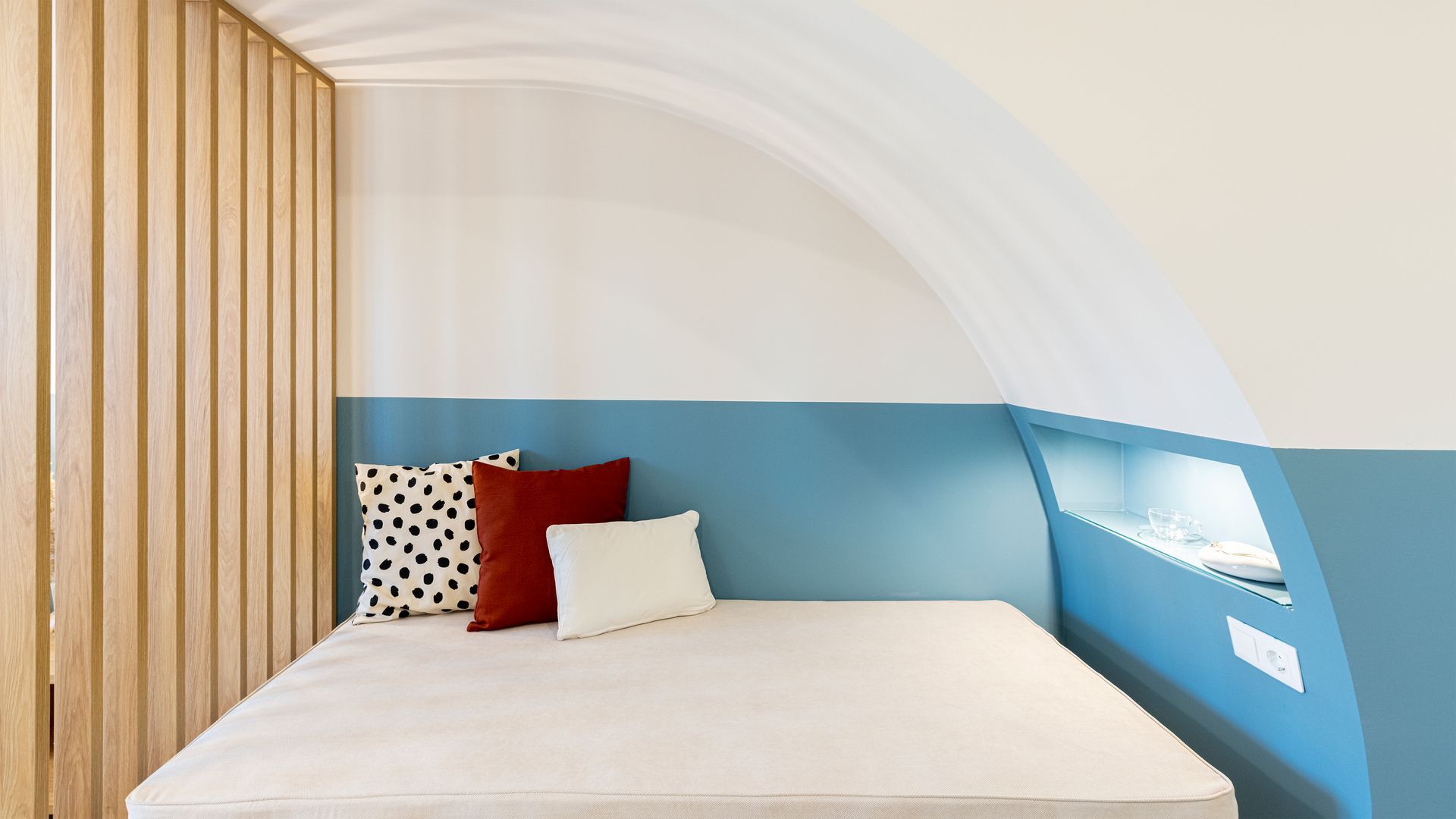 A bed with pillows on it in a room with a blue wall.