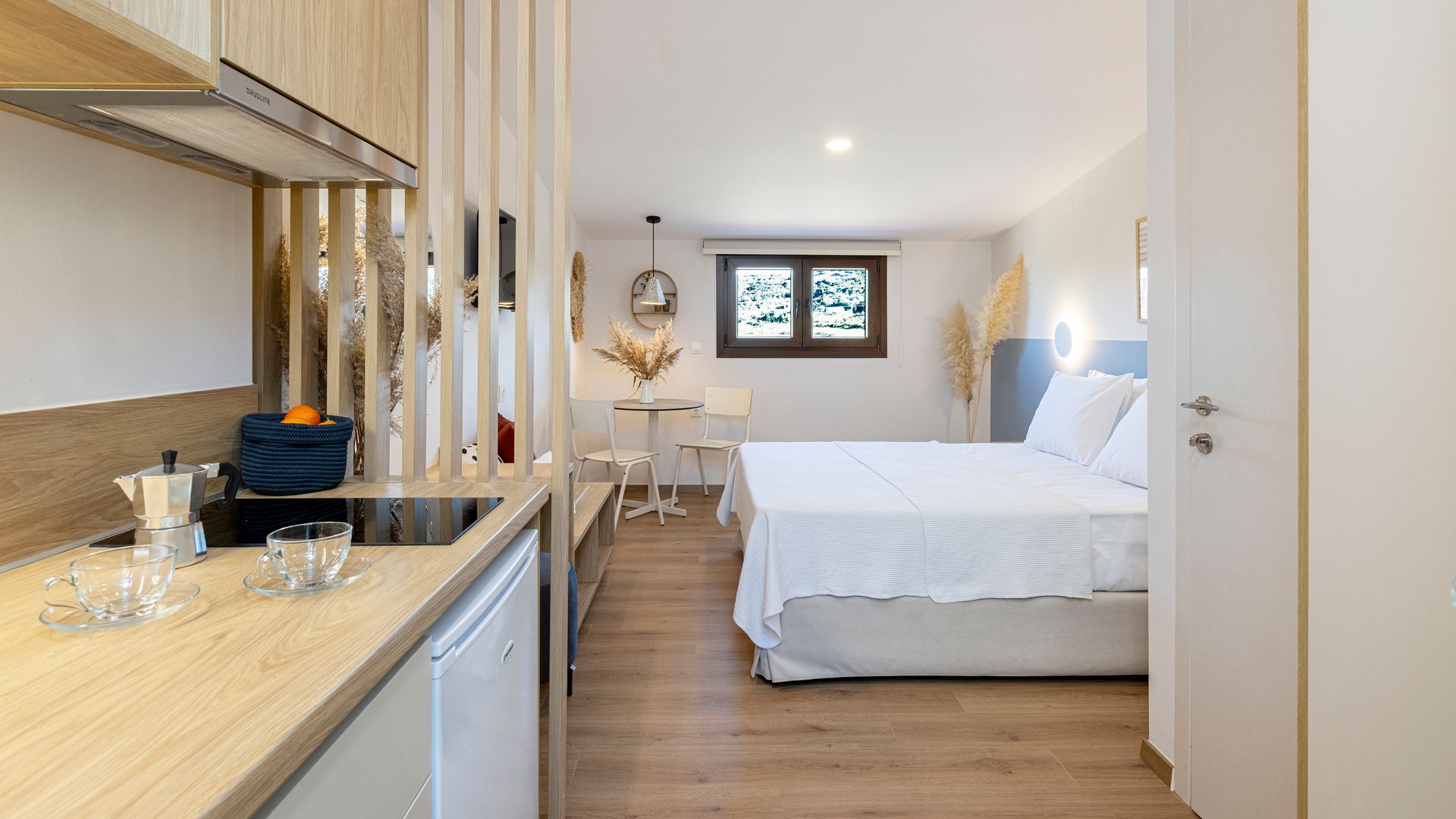 A bedroom with a bed and a kitchen in a small apartment.