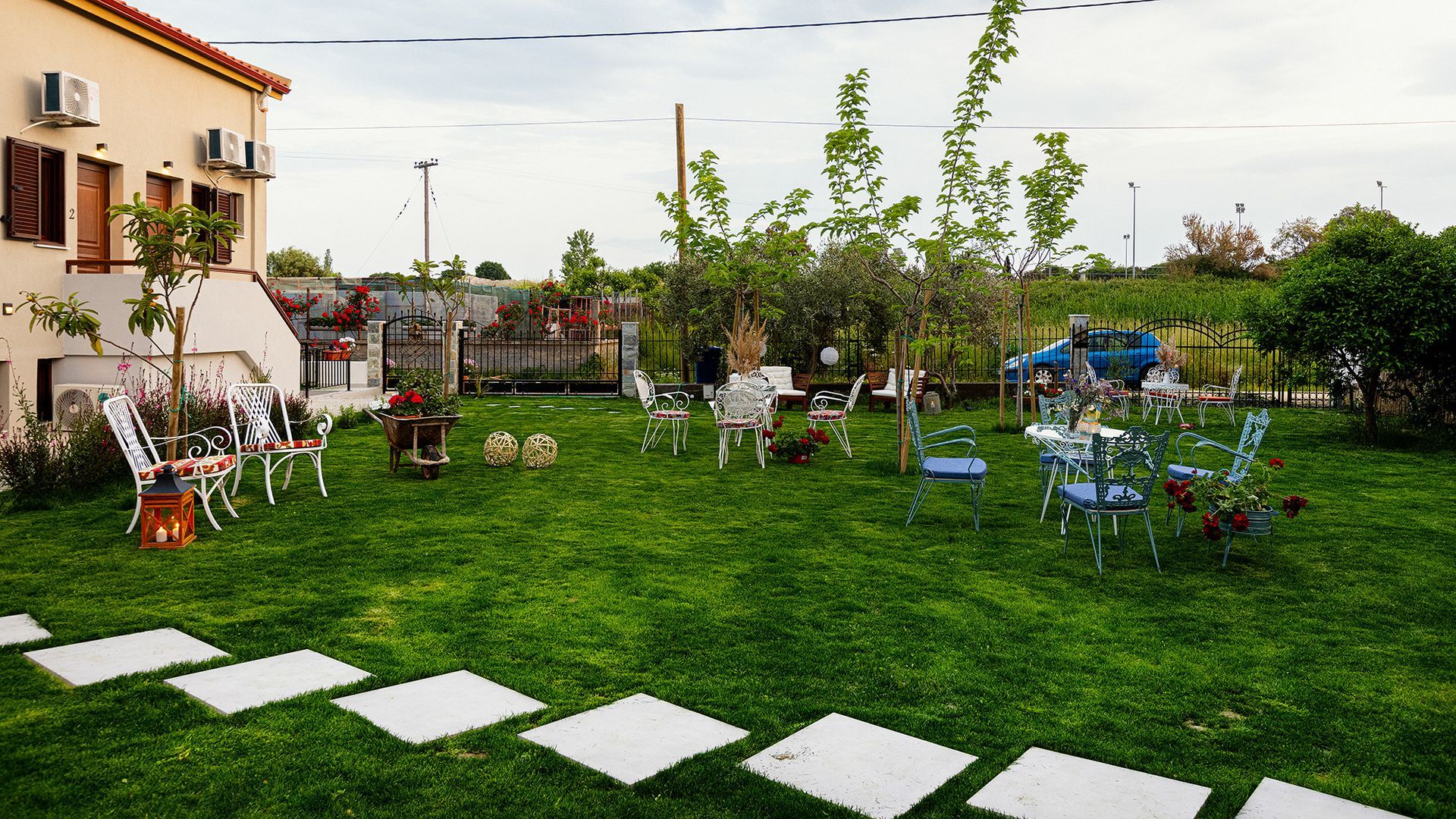 A lush green lawn with tables and chairs in front of a house.
