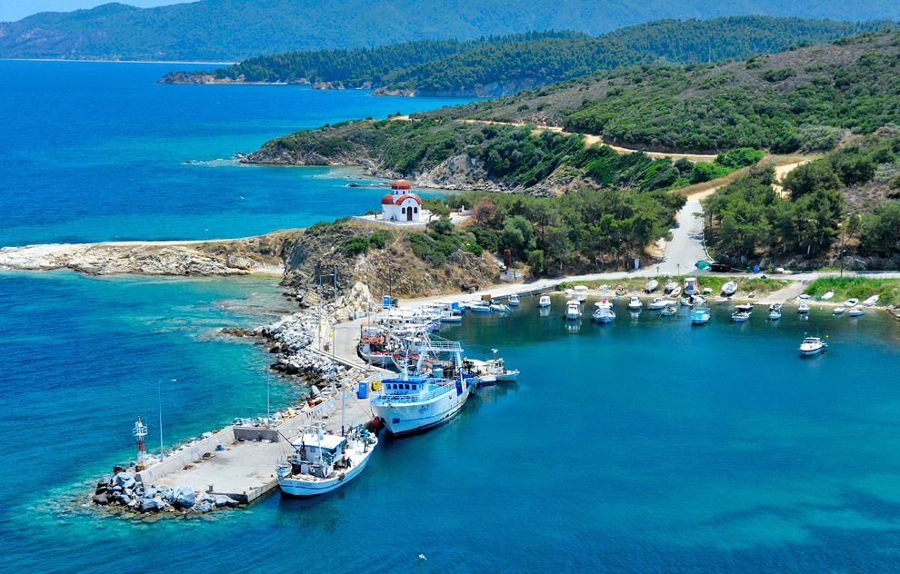 A group of boats are docked in a harbor on a small island.