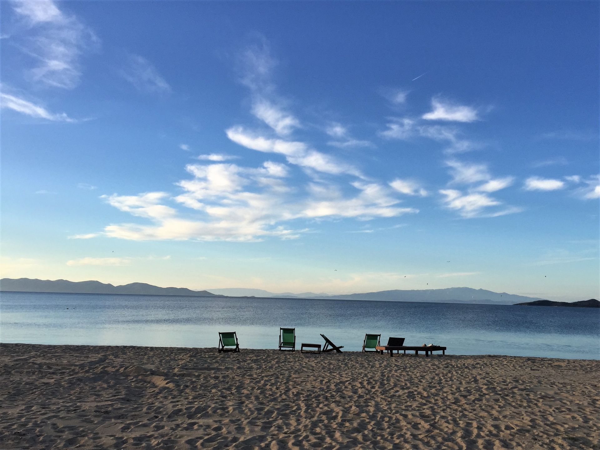 A beach with chairs on it and a body of water in the background.