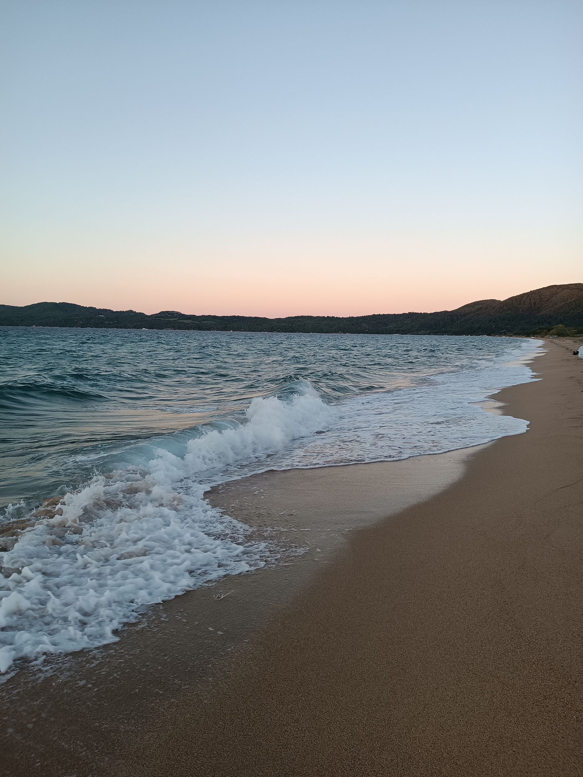 Waves crashing on a sandy beach at sunset