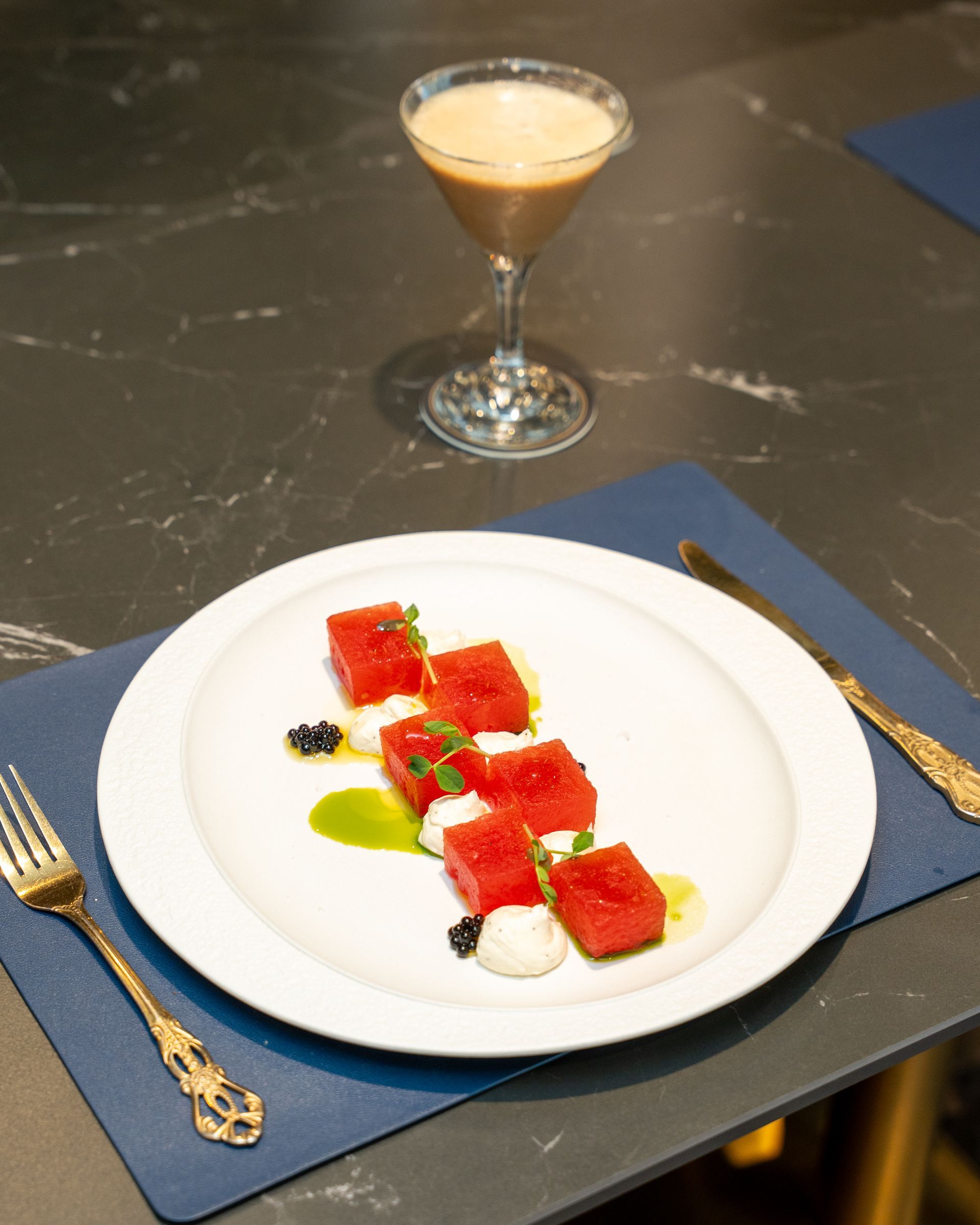 Watermelon and dessert cocktail on a table. Watermelon with sauce and caviar, cocktail in a martini glass.