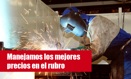 Soldador trabajando con chispas en un taller; pancarta roja que dice