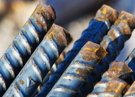 Primer plano de varias piezas de varillas de refuerzo oxidadas, que muestran metal azul y extremos texturizados.
