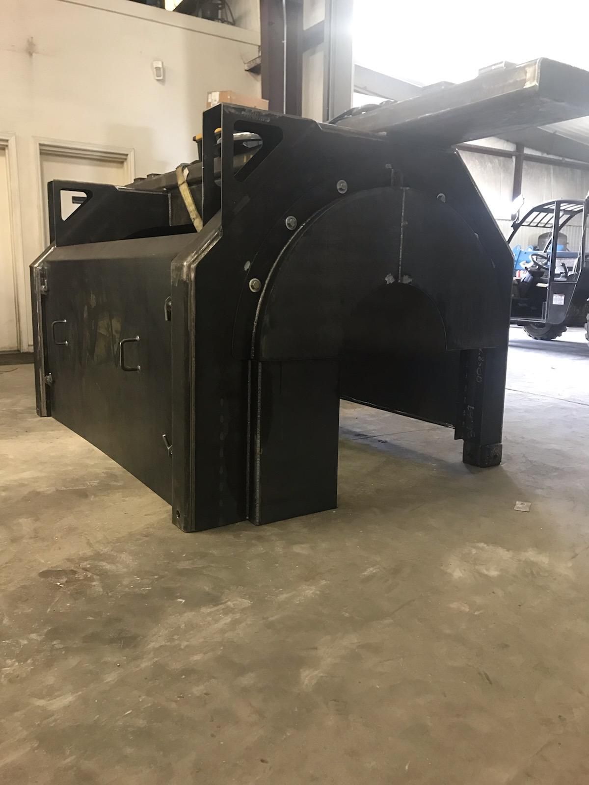 A large black machine is sitting on a concrete floor in a garage.