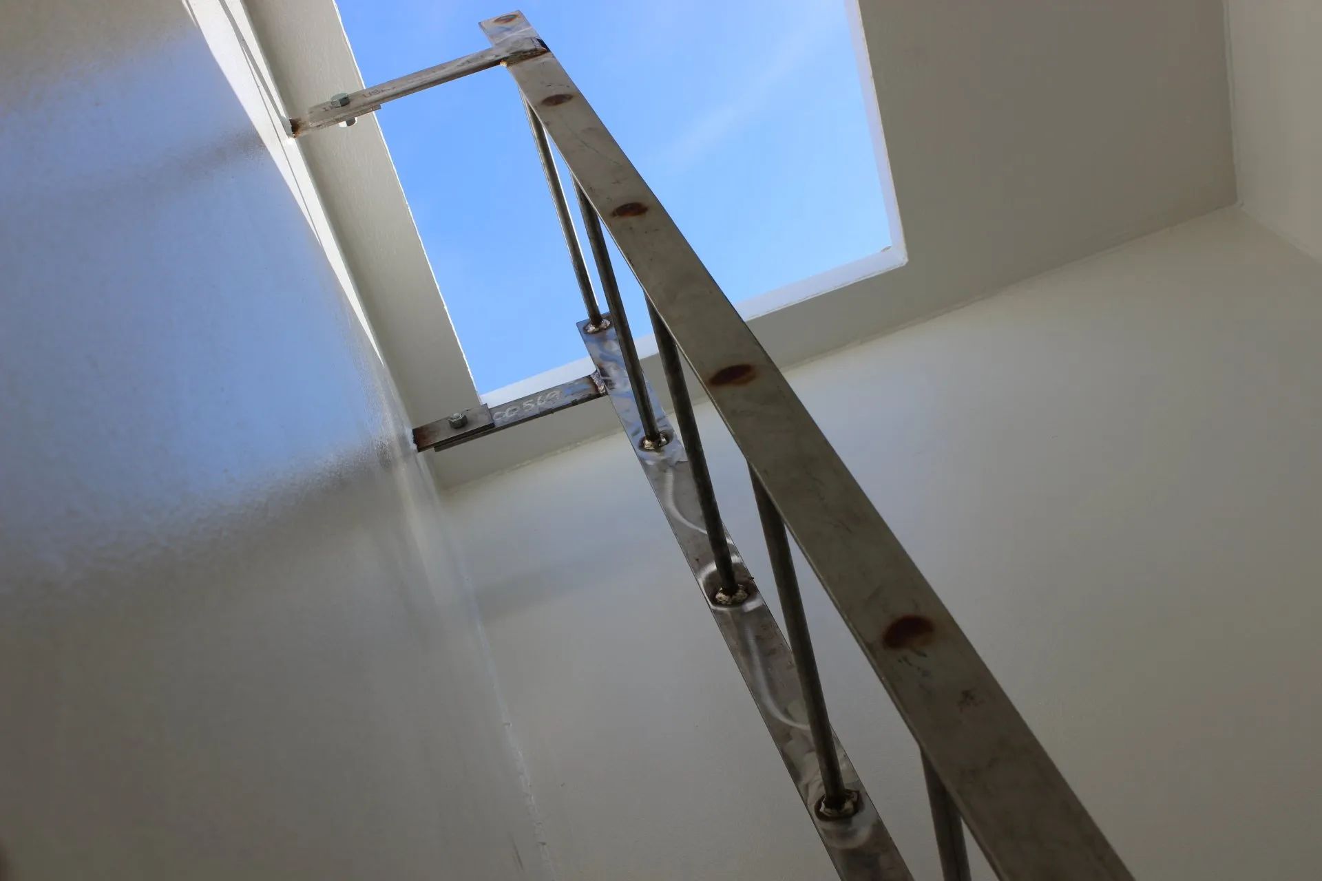 A ladder is going up to a skylight in a room.