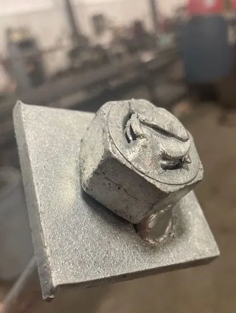 A close up of a metal object with a nut on top of it.