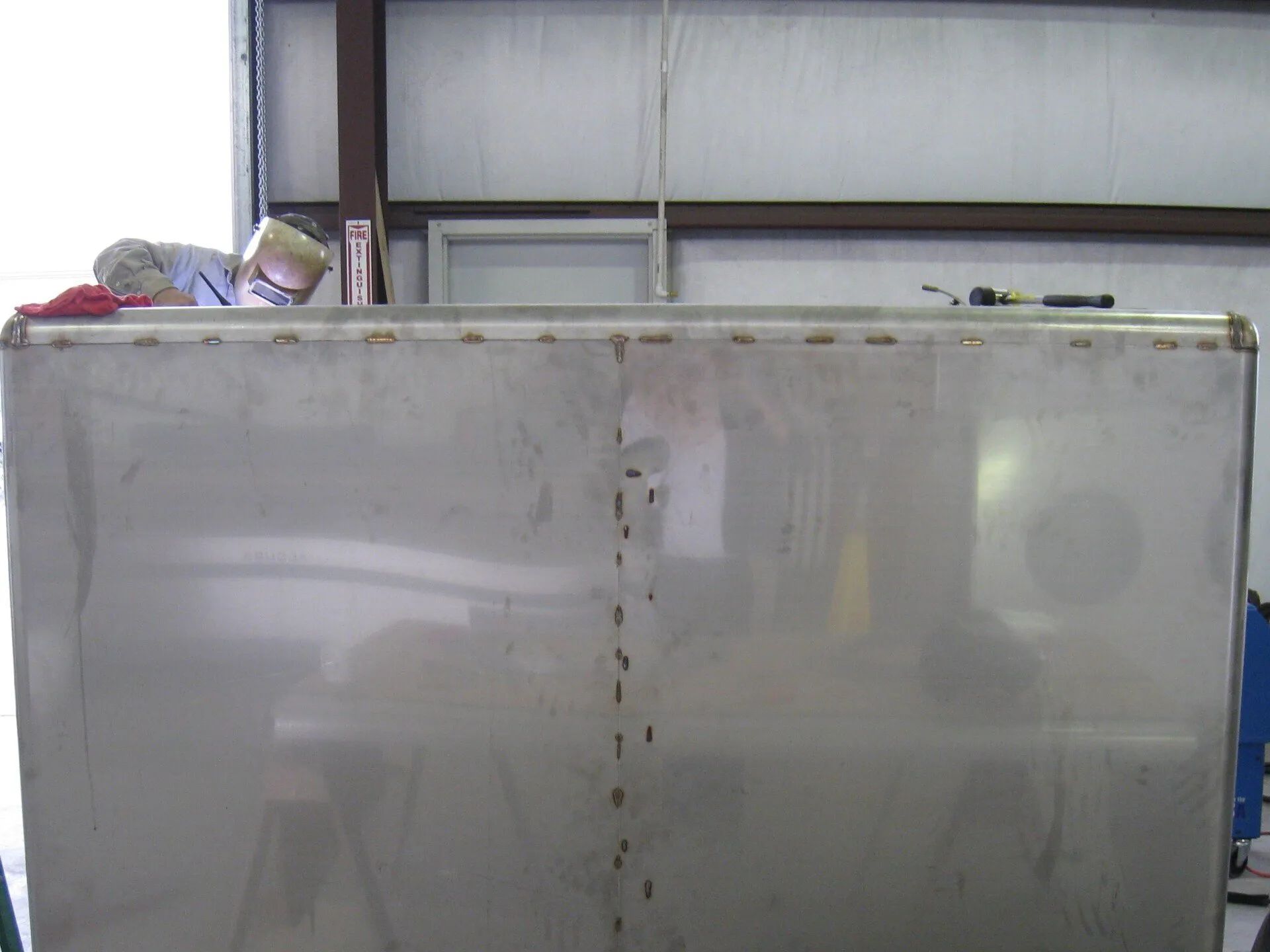 A large stainless steel container is sitting in a garage.