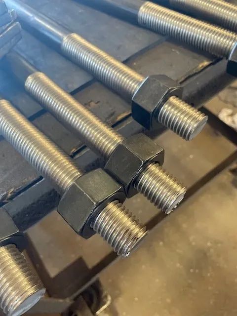 A bunch of nuts and bolts are stacked on top of each other on a table.