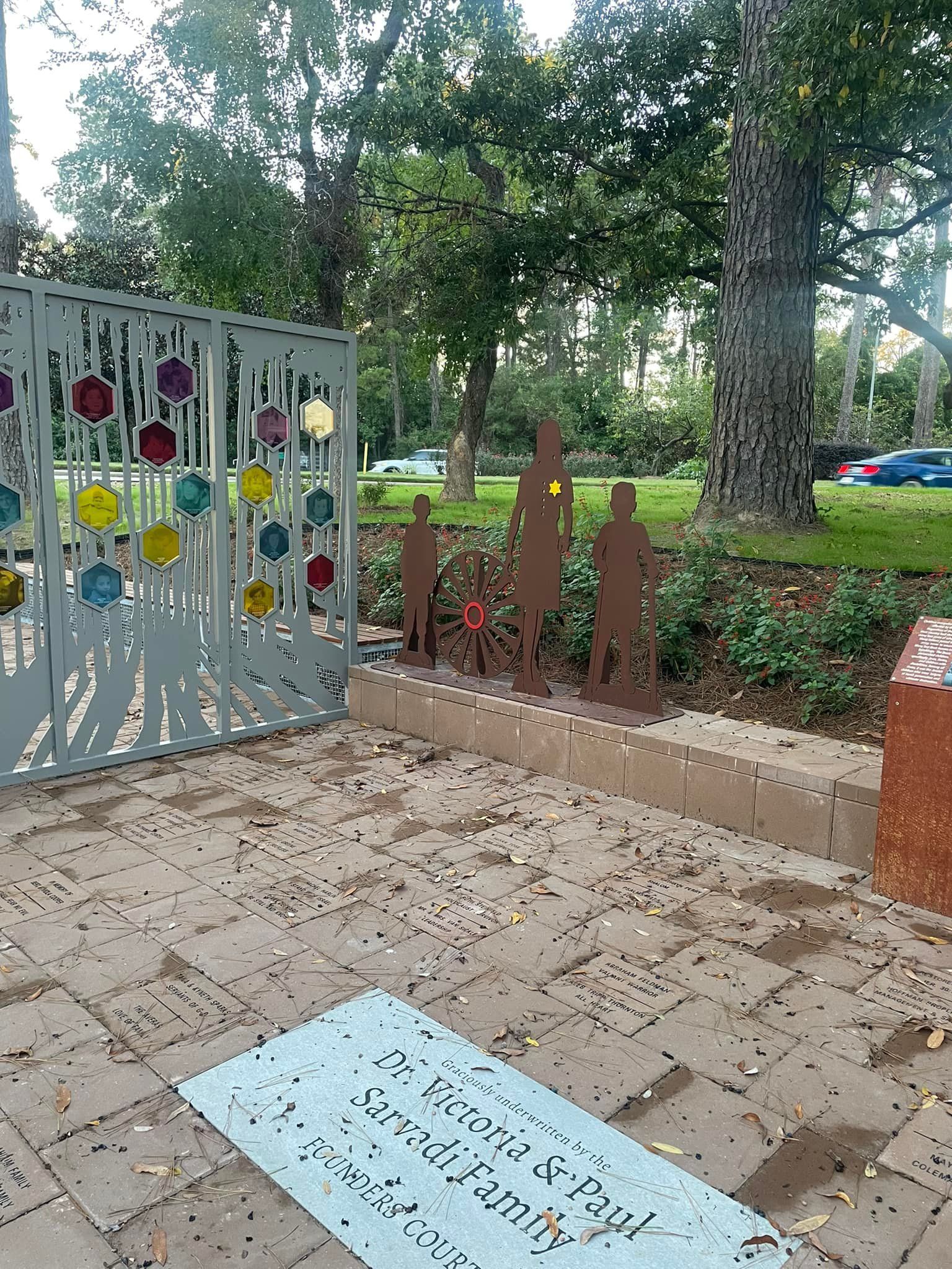 A sculpture of a family standing next to a fence in a park.