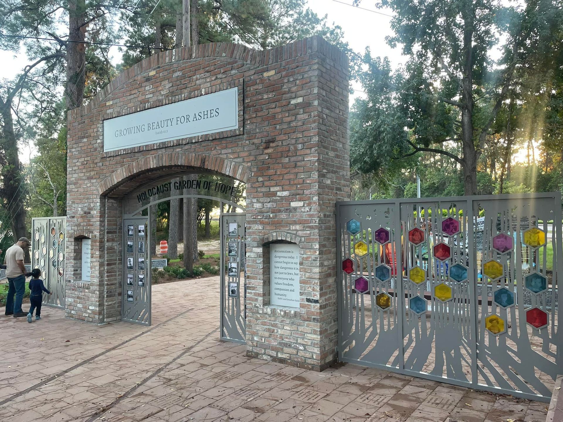 A man and a child are standing at the entrance to a park.