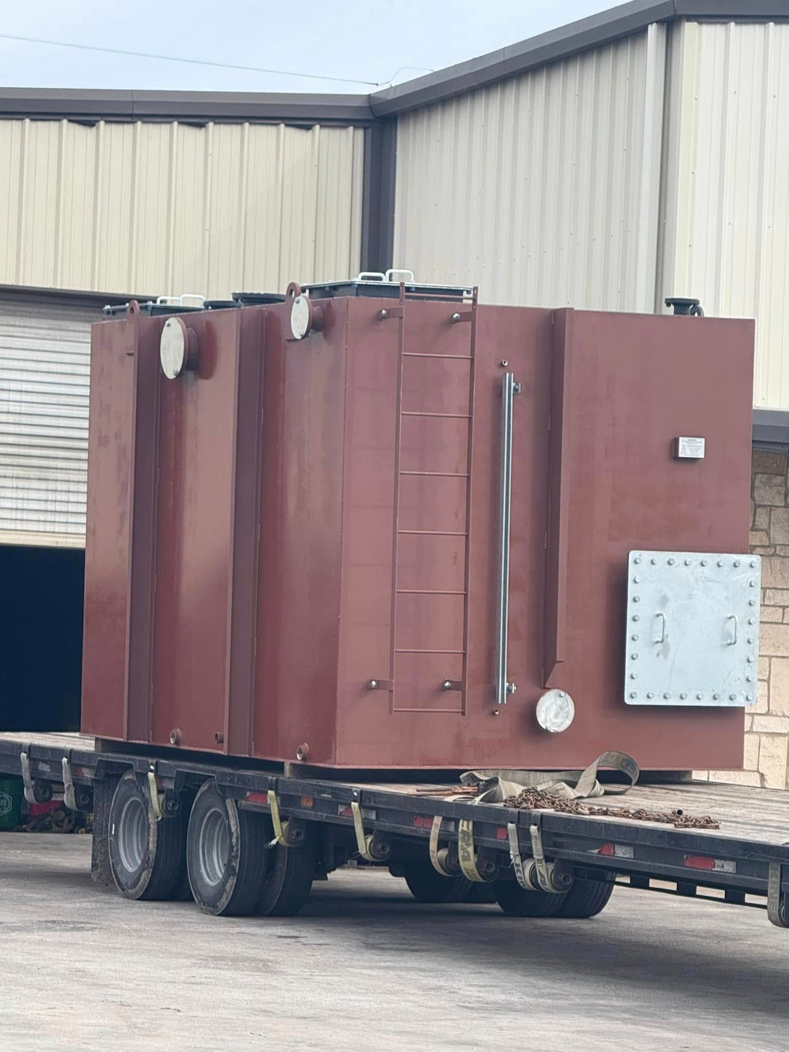 A large red container is on a trailer in front of a building.