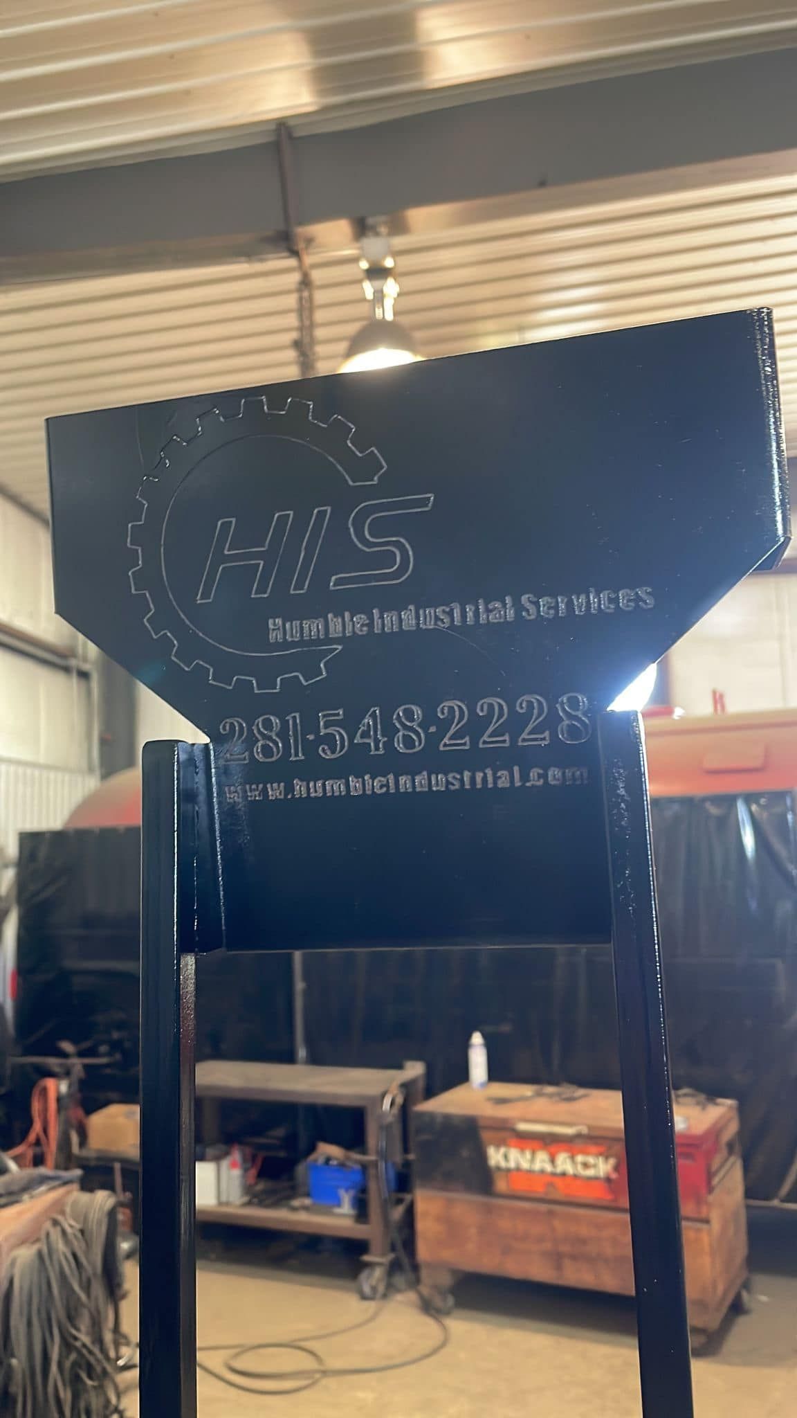 A large black sign is sitting in a room in a factory.