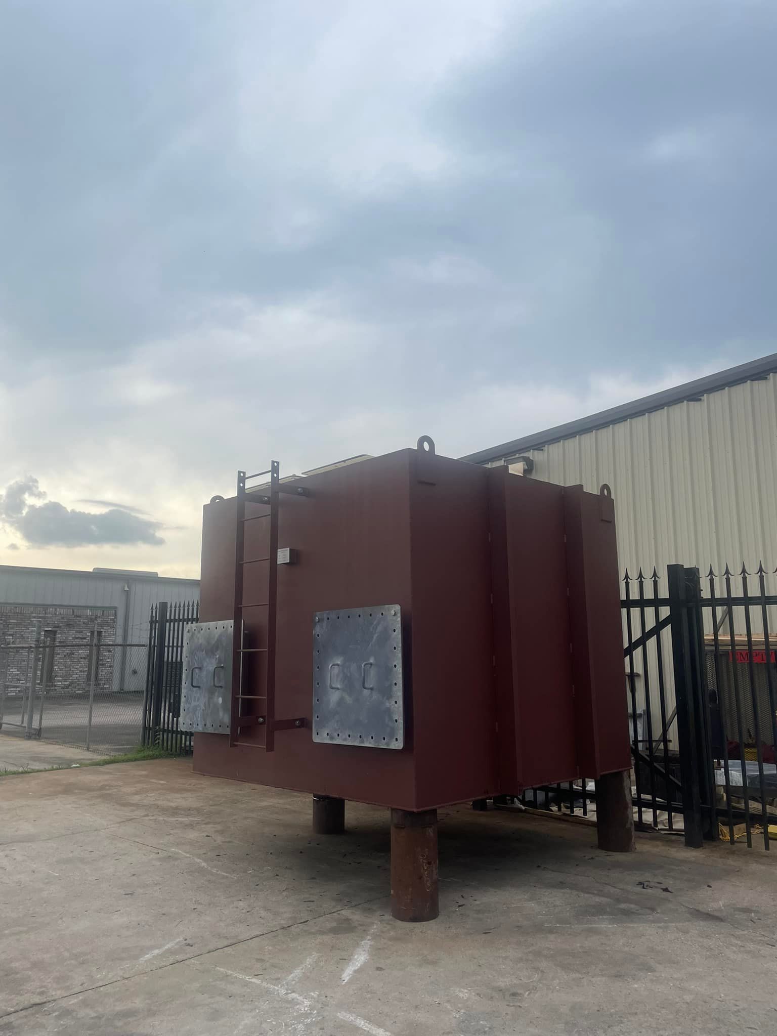 A large metal box is sitting in a parking lot in front of a building.