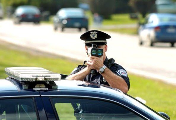 A police officer is taking a picture of a car with a camera