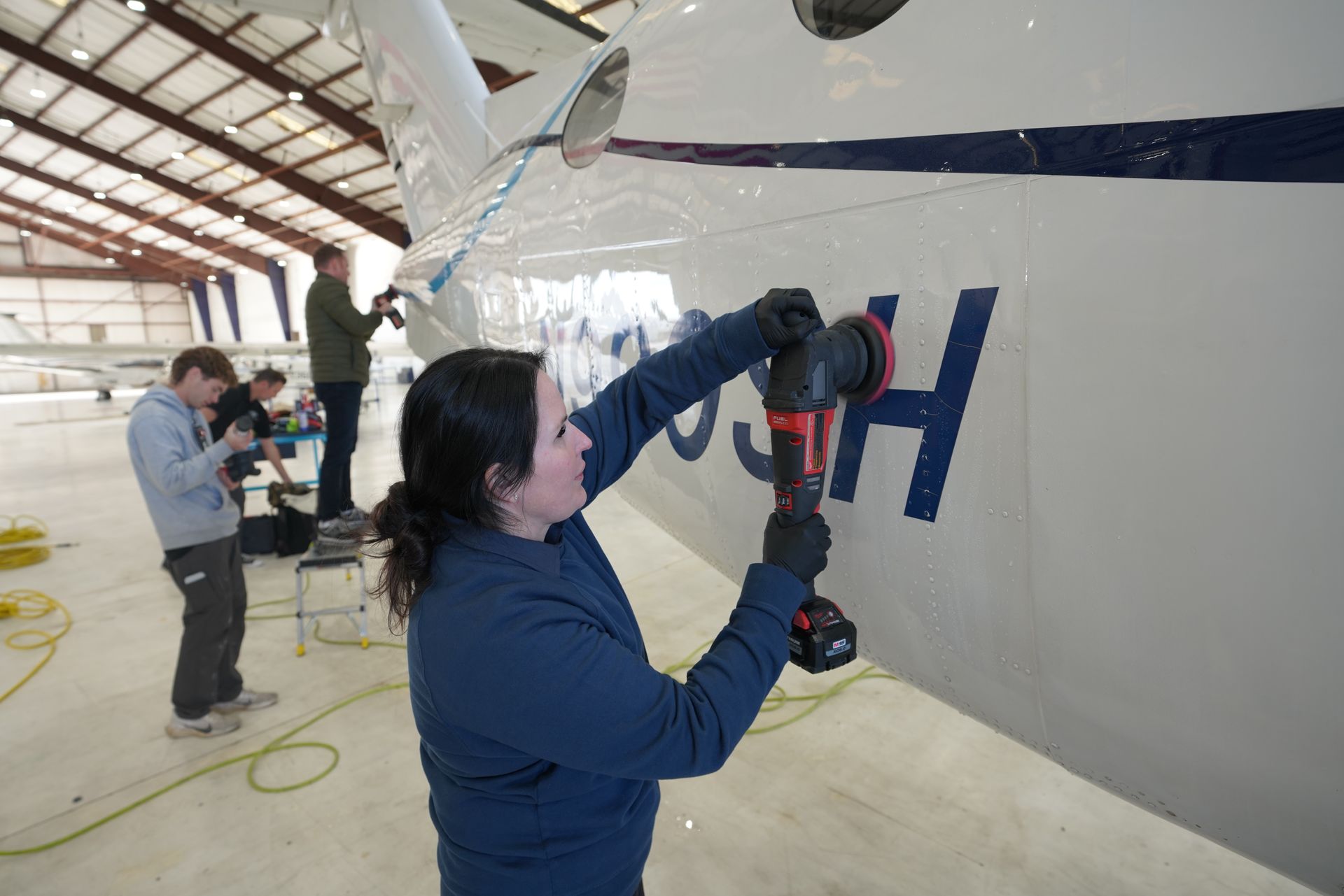 Aircraft paint correction polishing removing surface oxidation from fuselage inside hangar