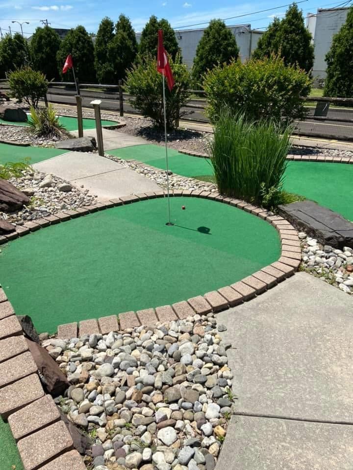 A small golf course with a red flag on the green.