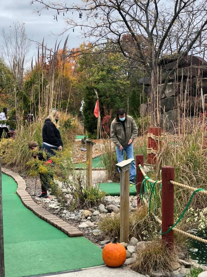 A group of people are playing mini golf in a park.