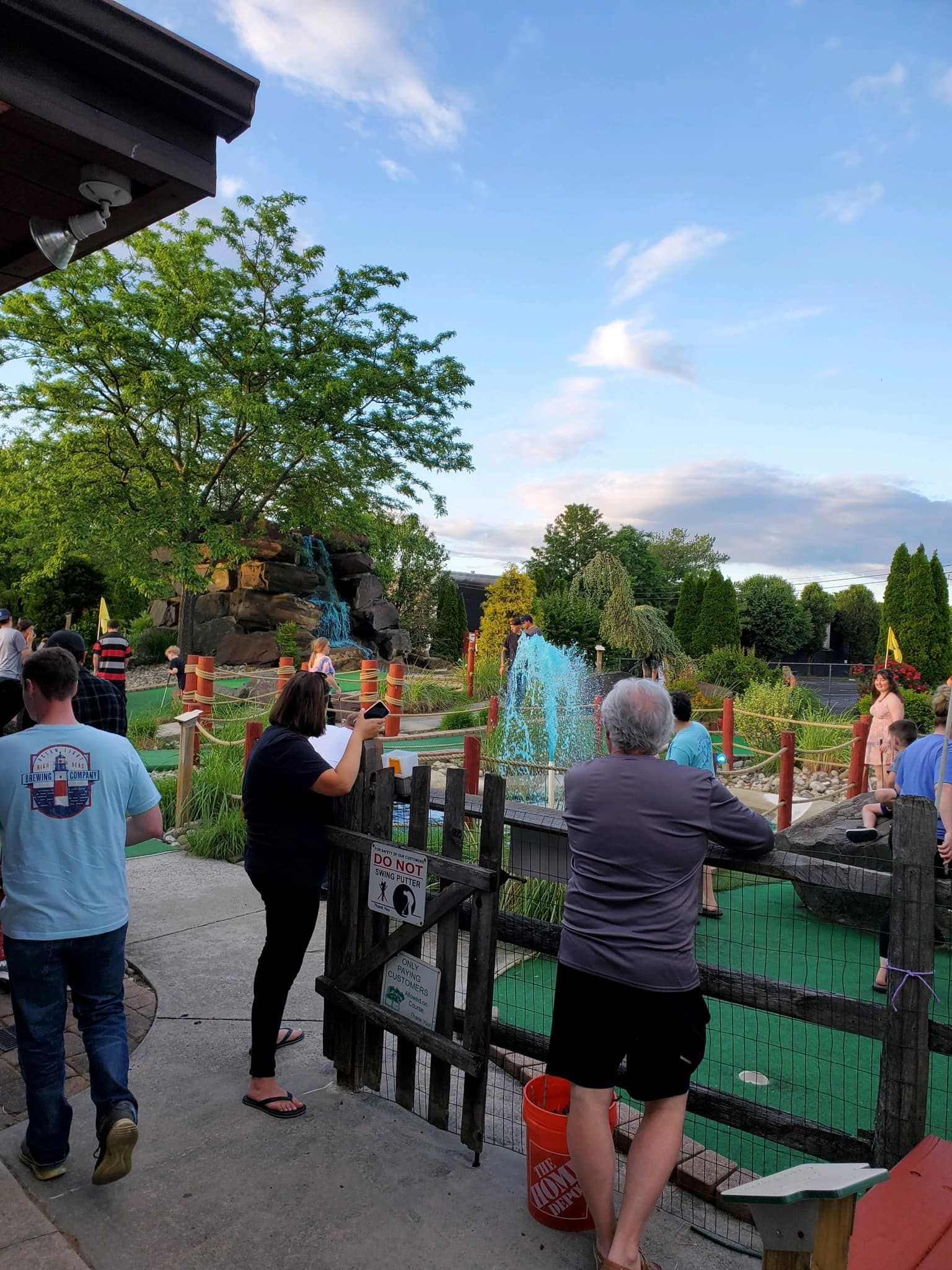 A group of people are standing in front of a mini golf course.