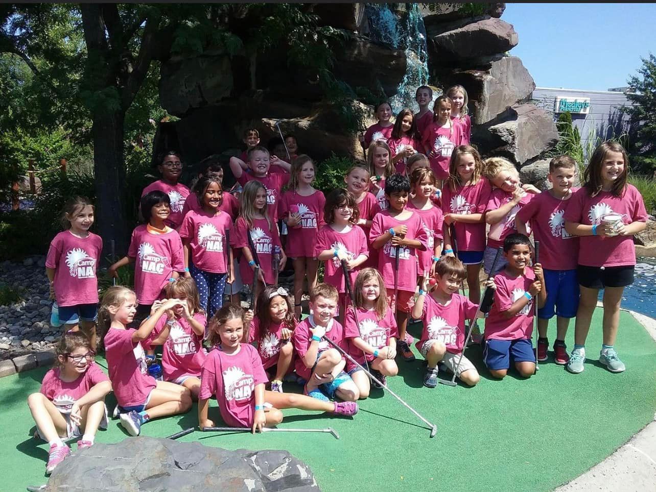 A group of children wearing pink shirts are posing for a picture