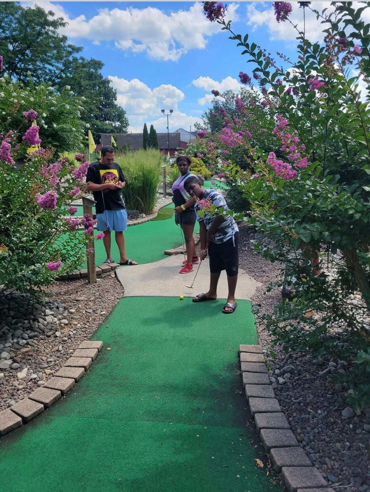 A group of people are playing mini golf in a park