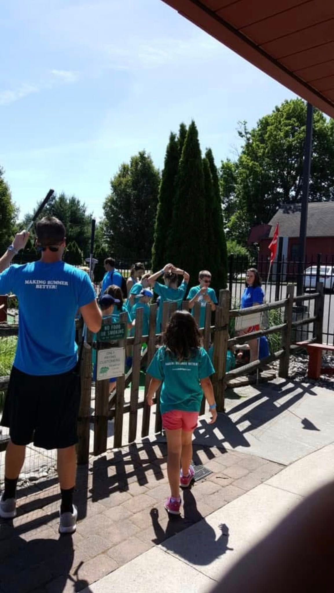 A man in a blue shirt is standing next to a girl in a green shirt.